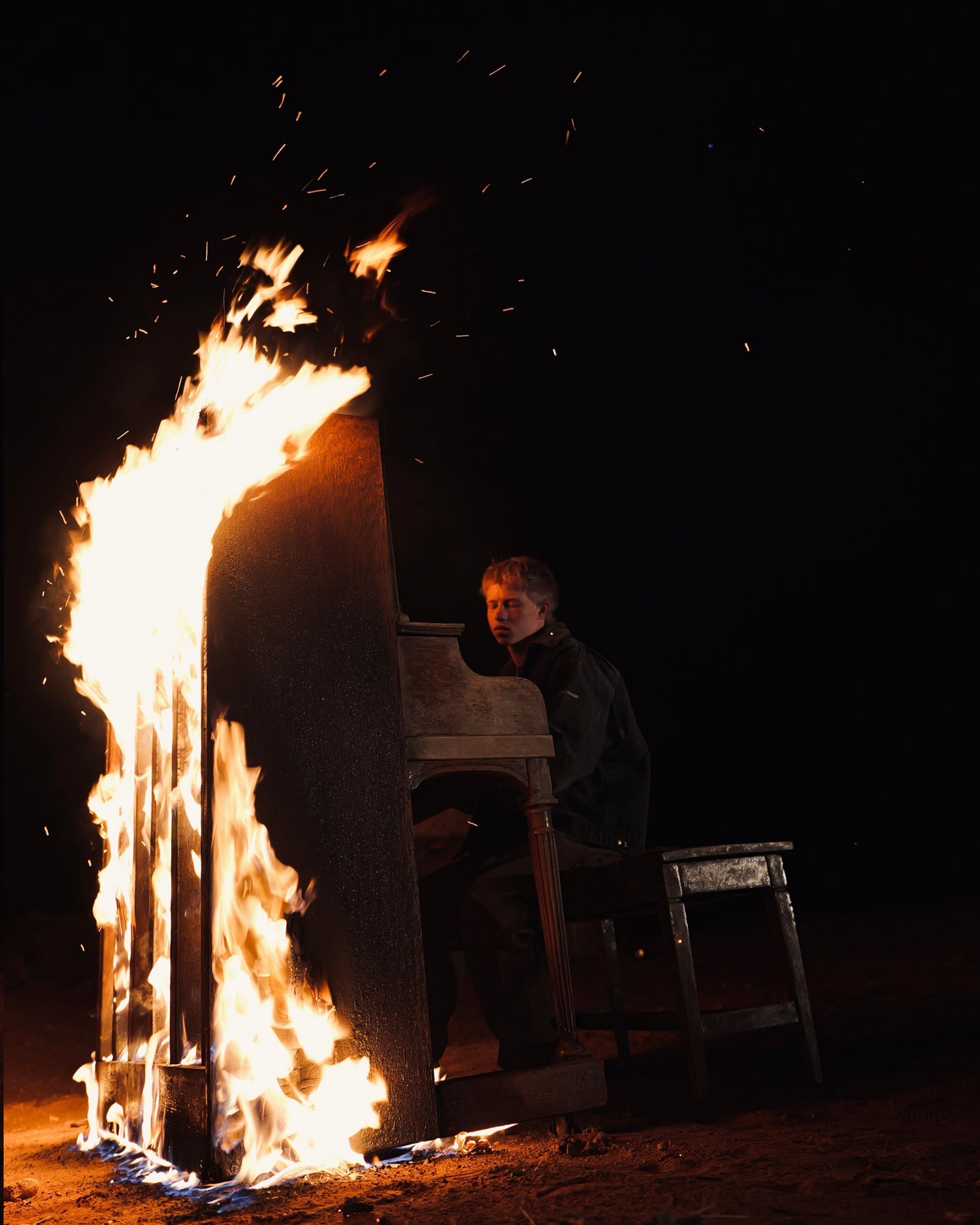Piano on fire with a person observing in a dark setting