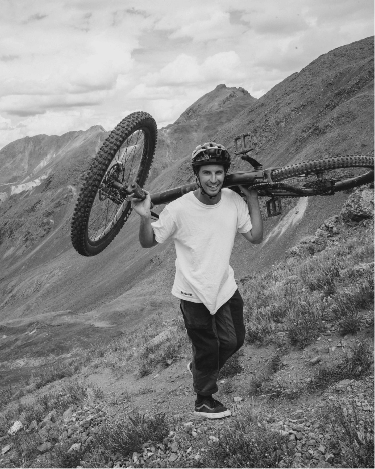 Person carrying a mountain bike on a mountainous landscape