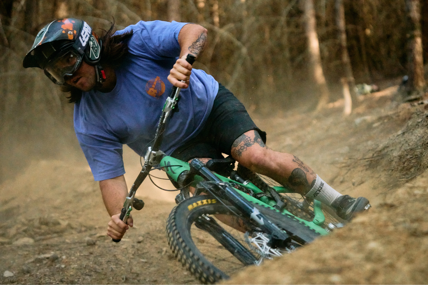 Person riding a mountain bike on a dirt trail with a helmet and goggles.