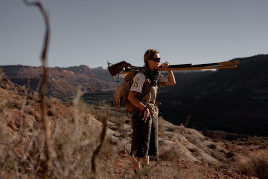 Lucy standing in the desert holding a bunch of tools