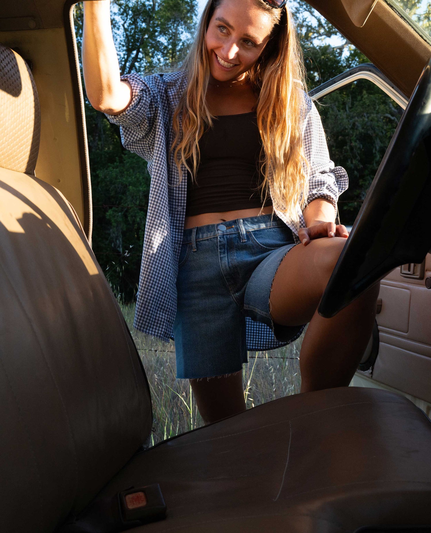 Girl wearing blue denim shorts and black shirt, stepping into a truck. 