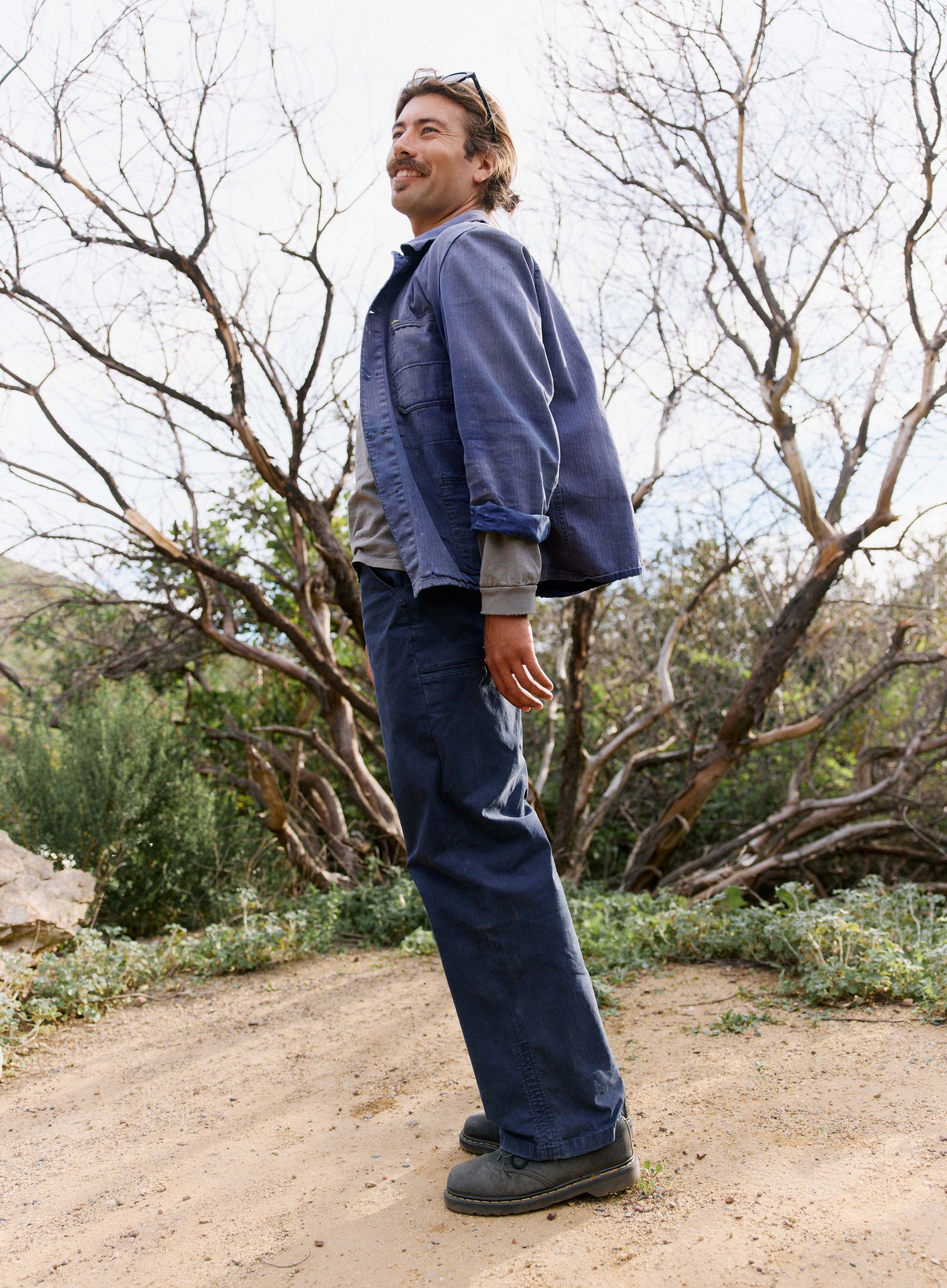 Man standing outdoors in a natural setting wearing a blue jacket and pants.