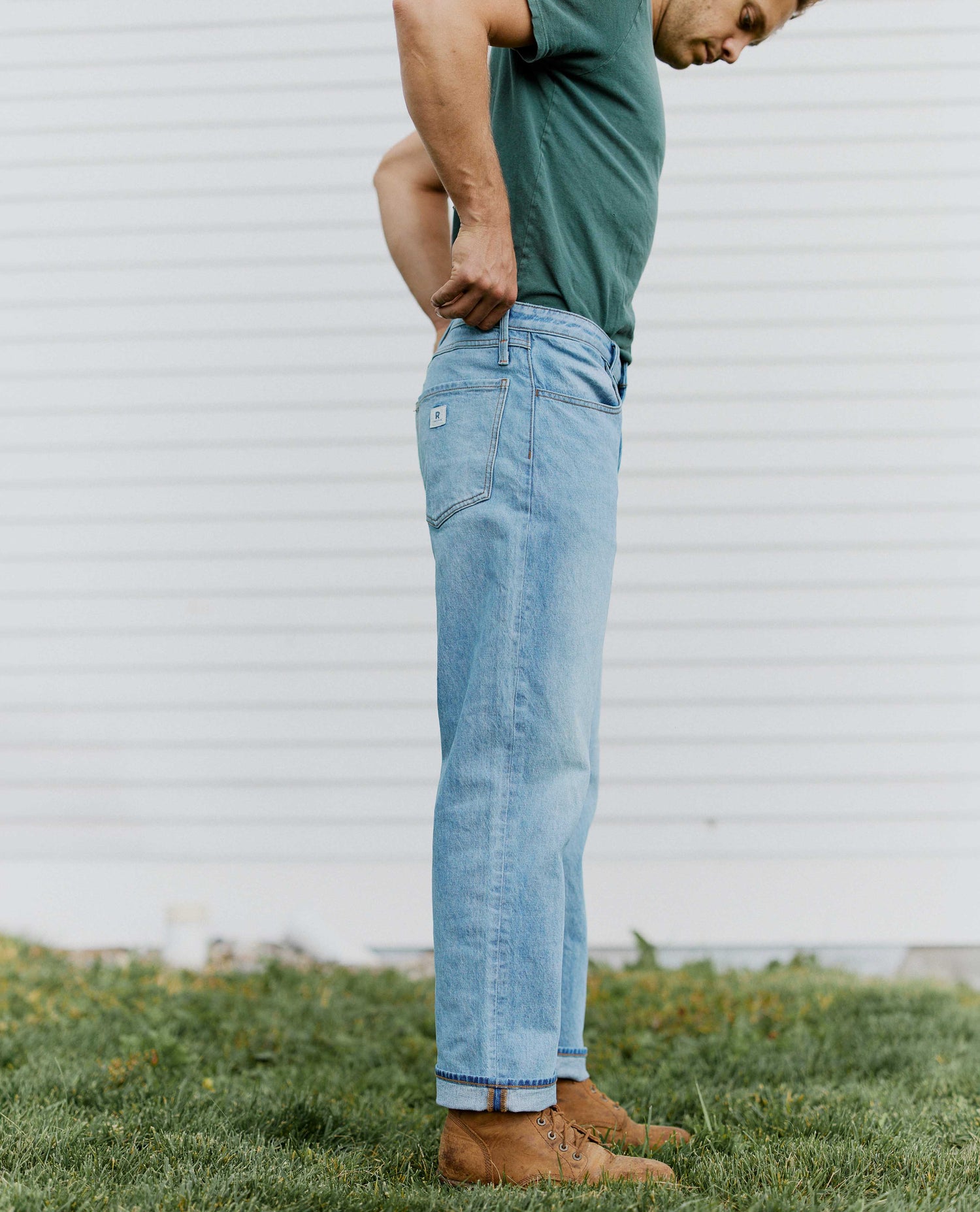 Man pulling up on the waist of his jeans standing sideways