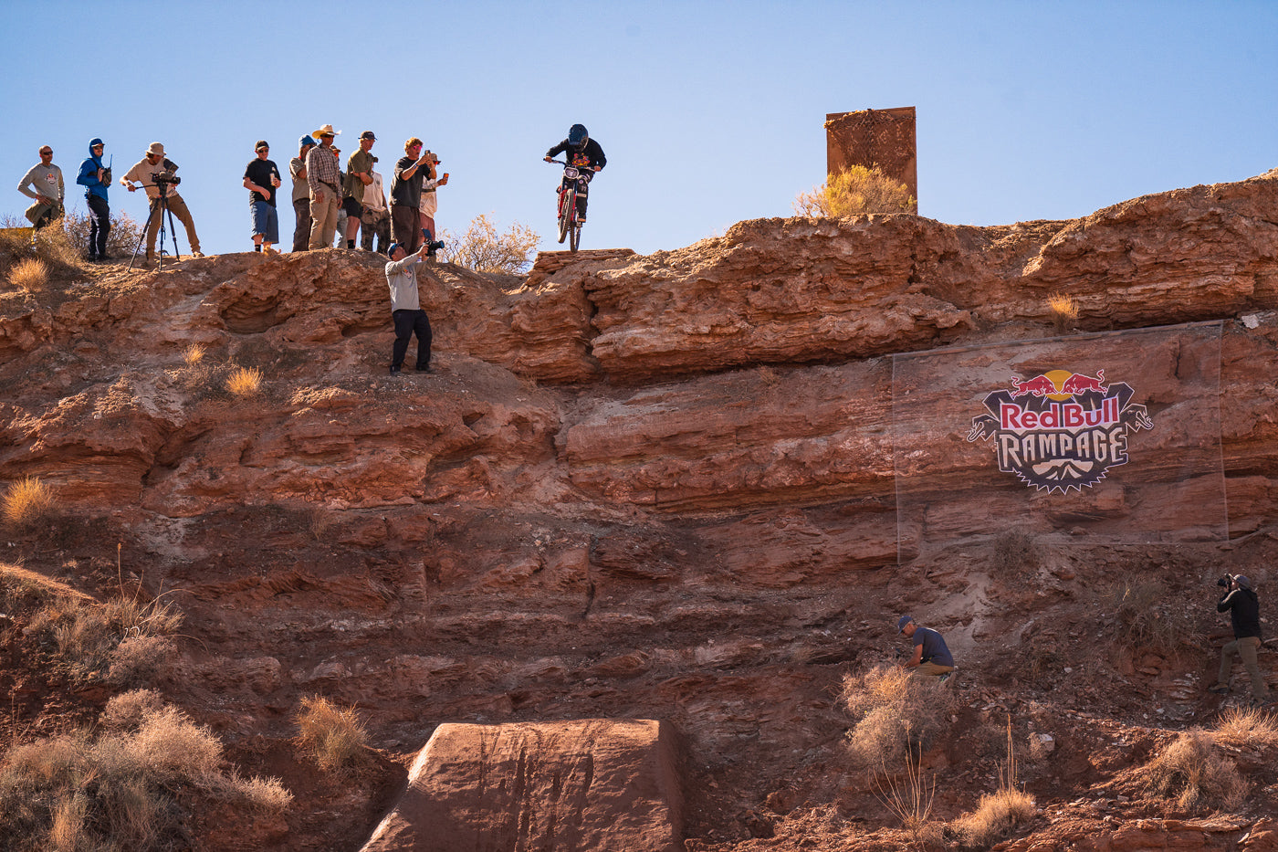 People on a rocky cliff with Red Bull Rampage logo