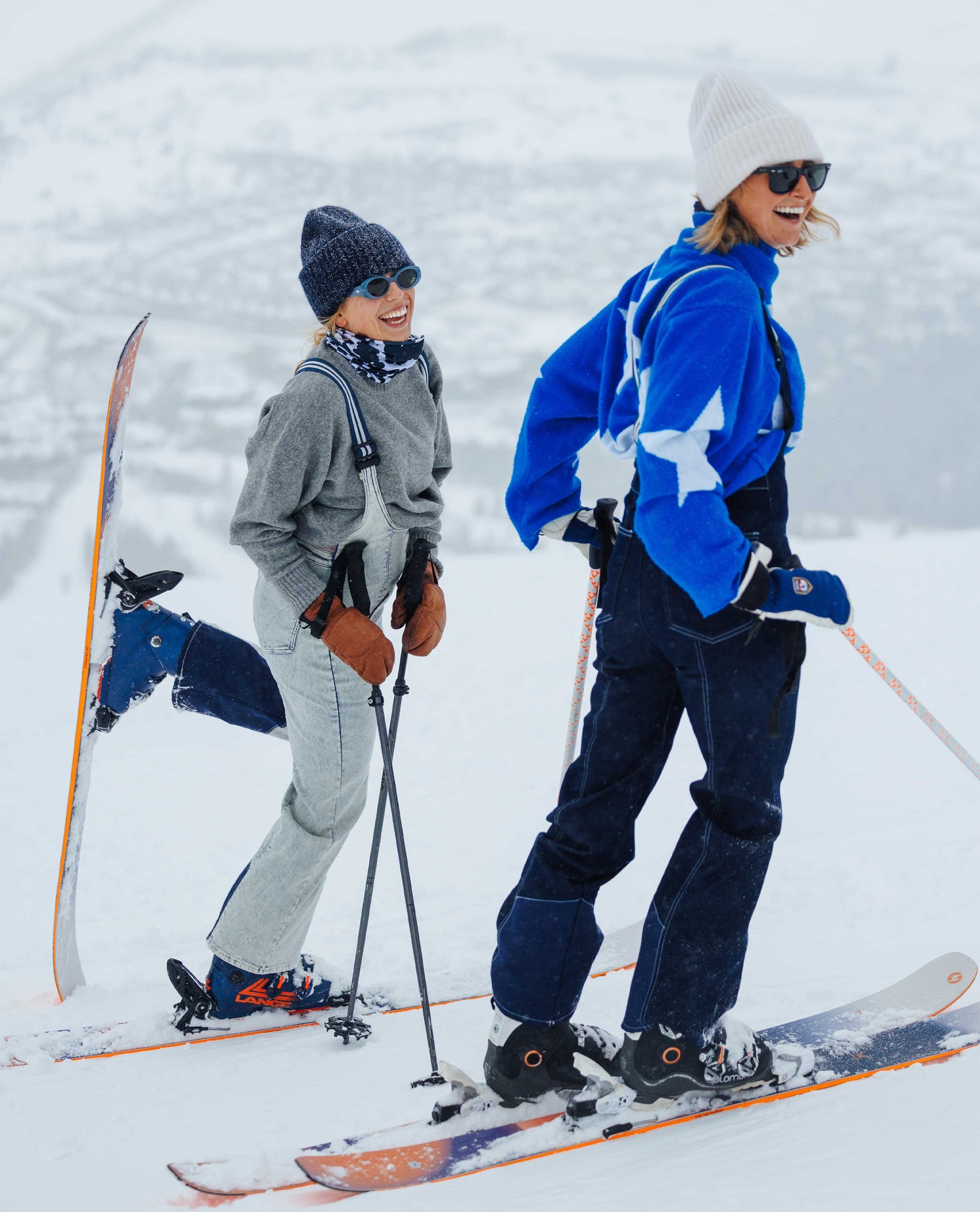 Two people skiing on a snowy slope with skis and ski poles.