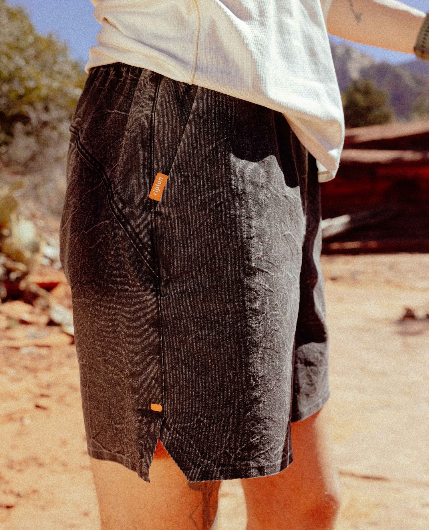 Person wearing dark shorts with orange buttons in a natural setting