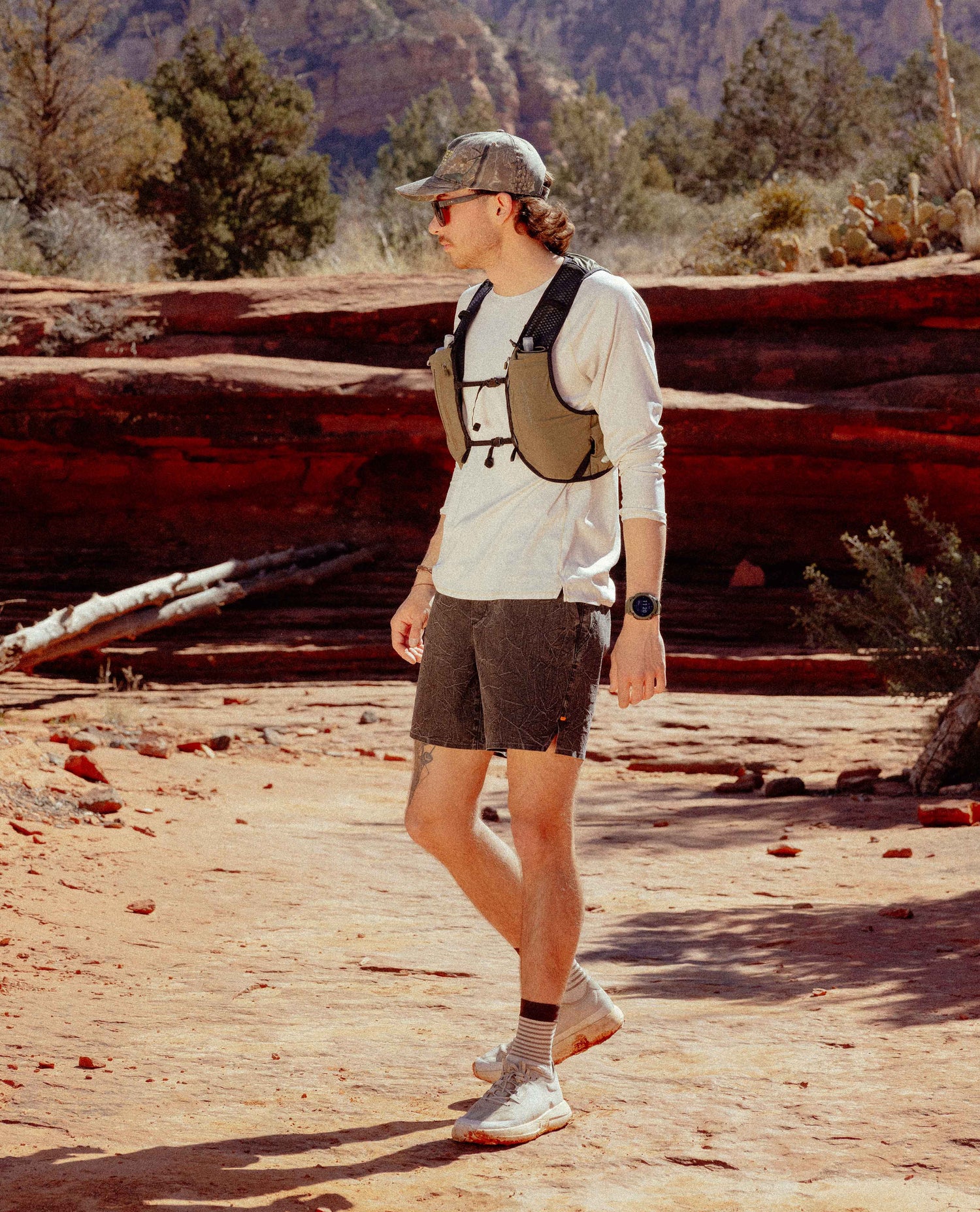 Man hiking in a desert landscape with red rock formations.