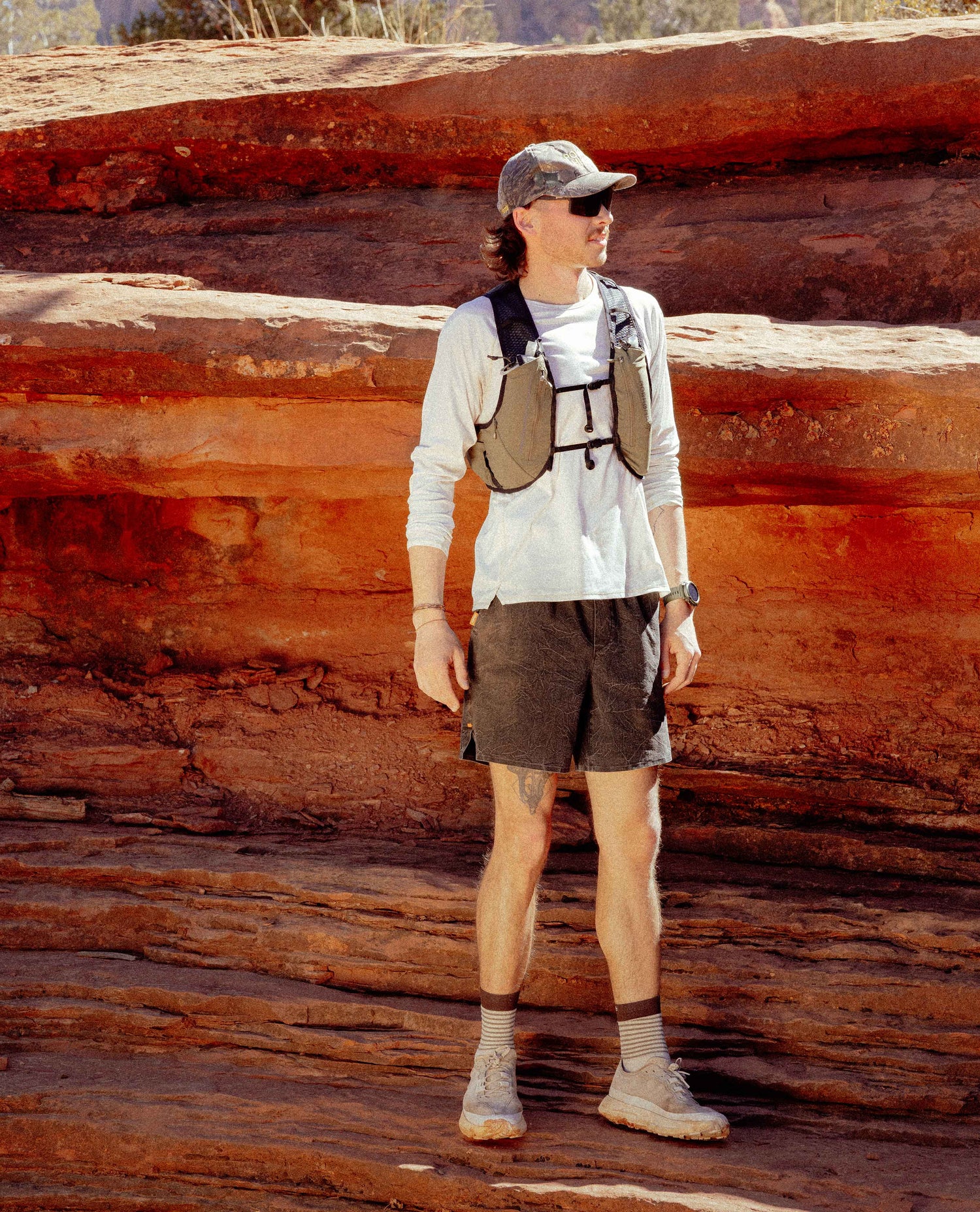 Person standing on a rocky landscape wearing a backpack and sunglasses.