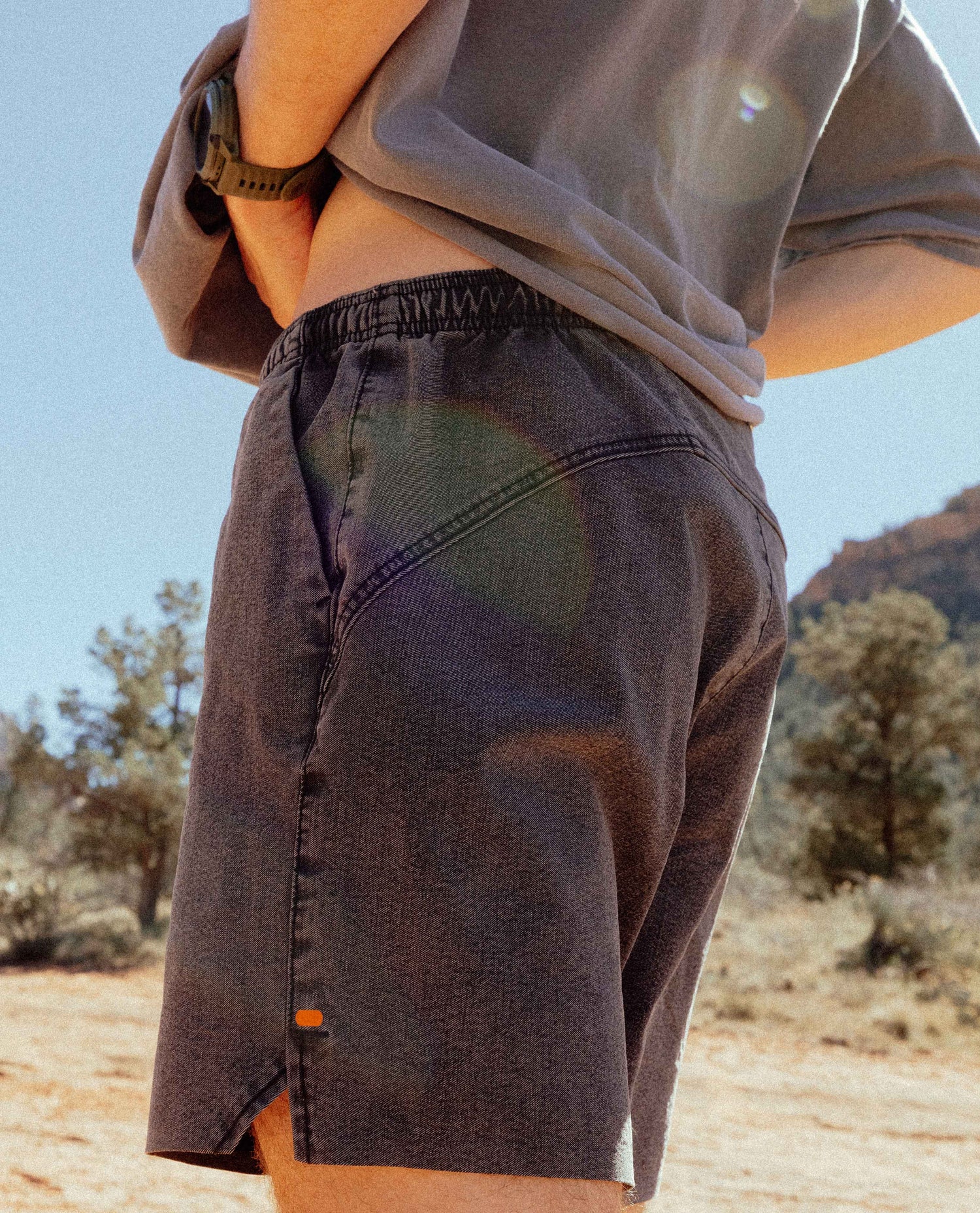 Person wearing brown shorts and a light shirt in a desert setting