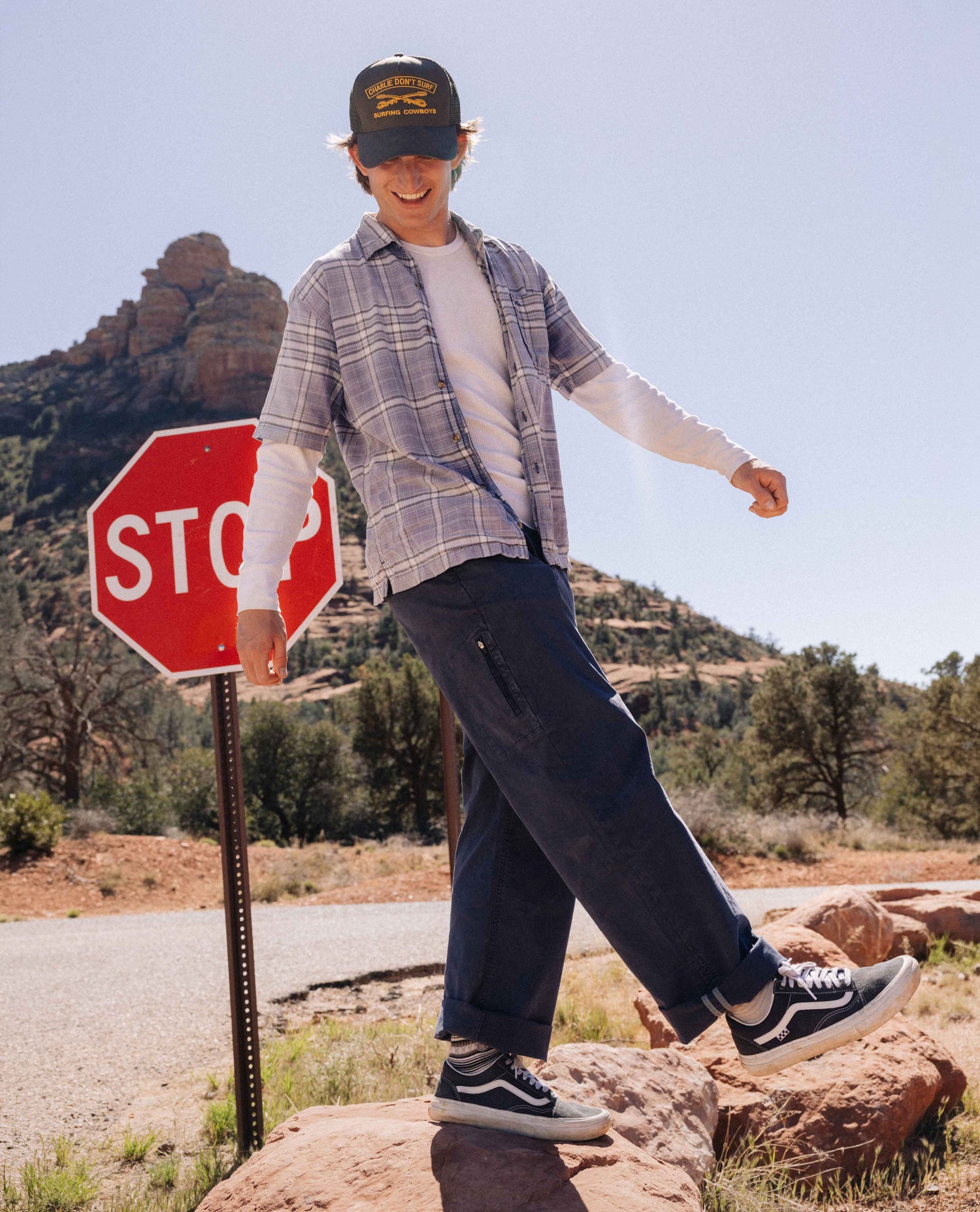 Person standing on a rock by a stop sign with a scenic background
