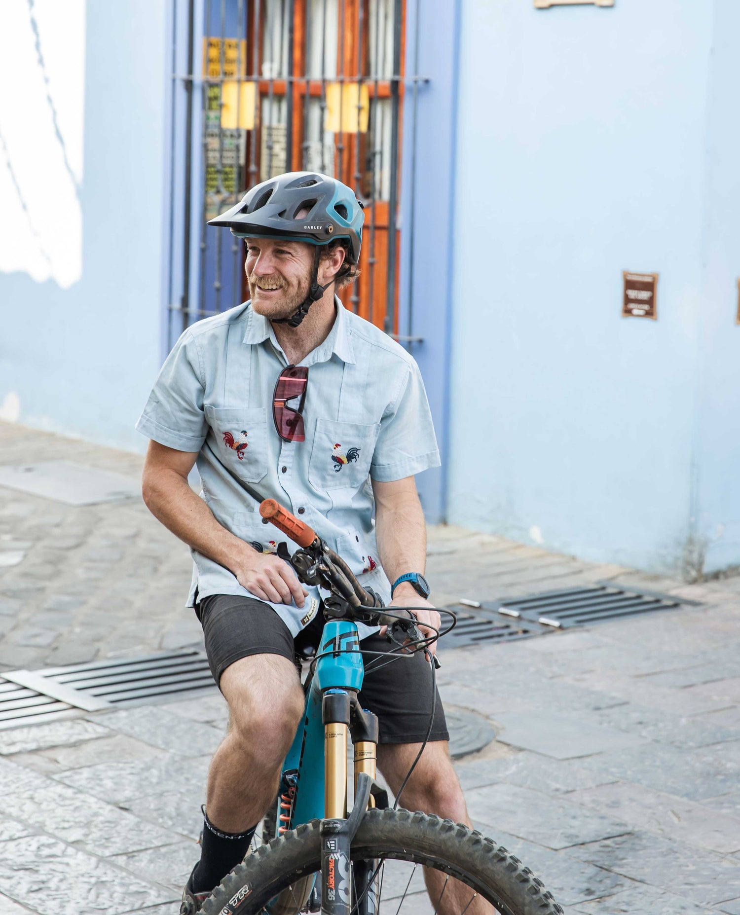 Man in blue shirt on bike outside in front of blue wall and door