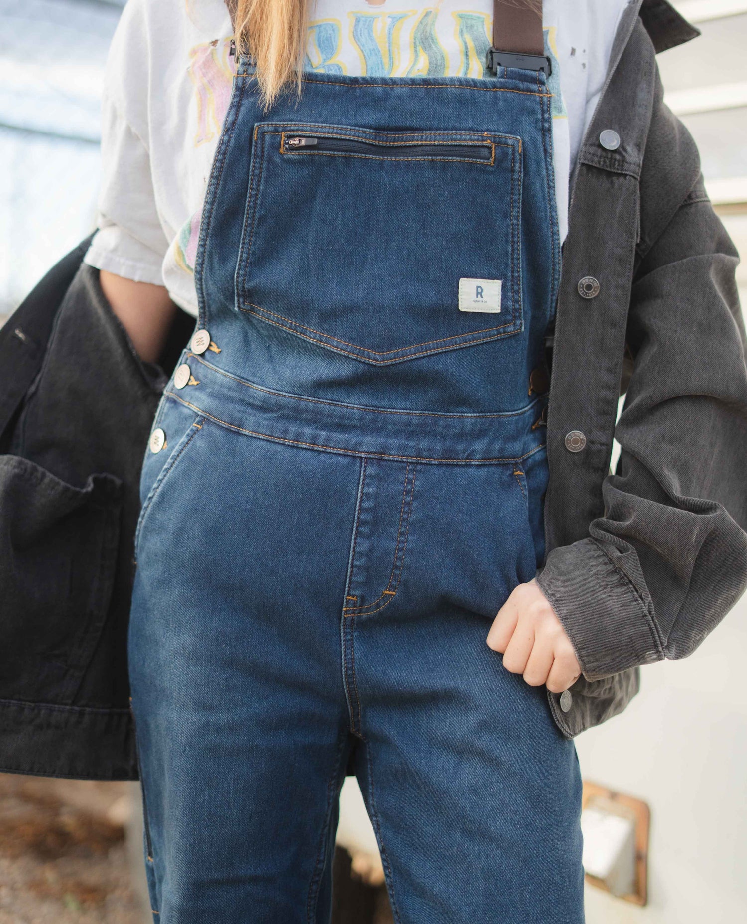 Person wearing blue denim overalls with a blurred background