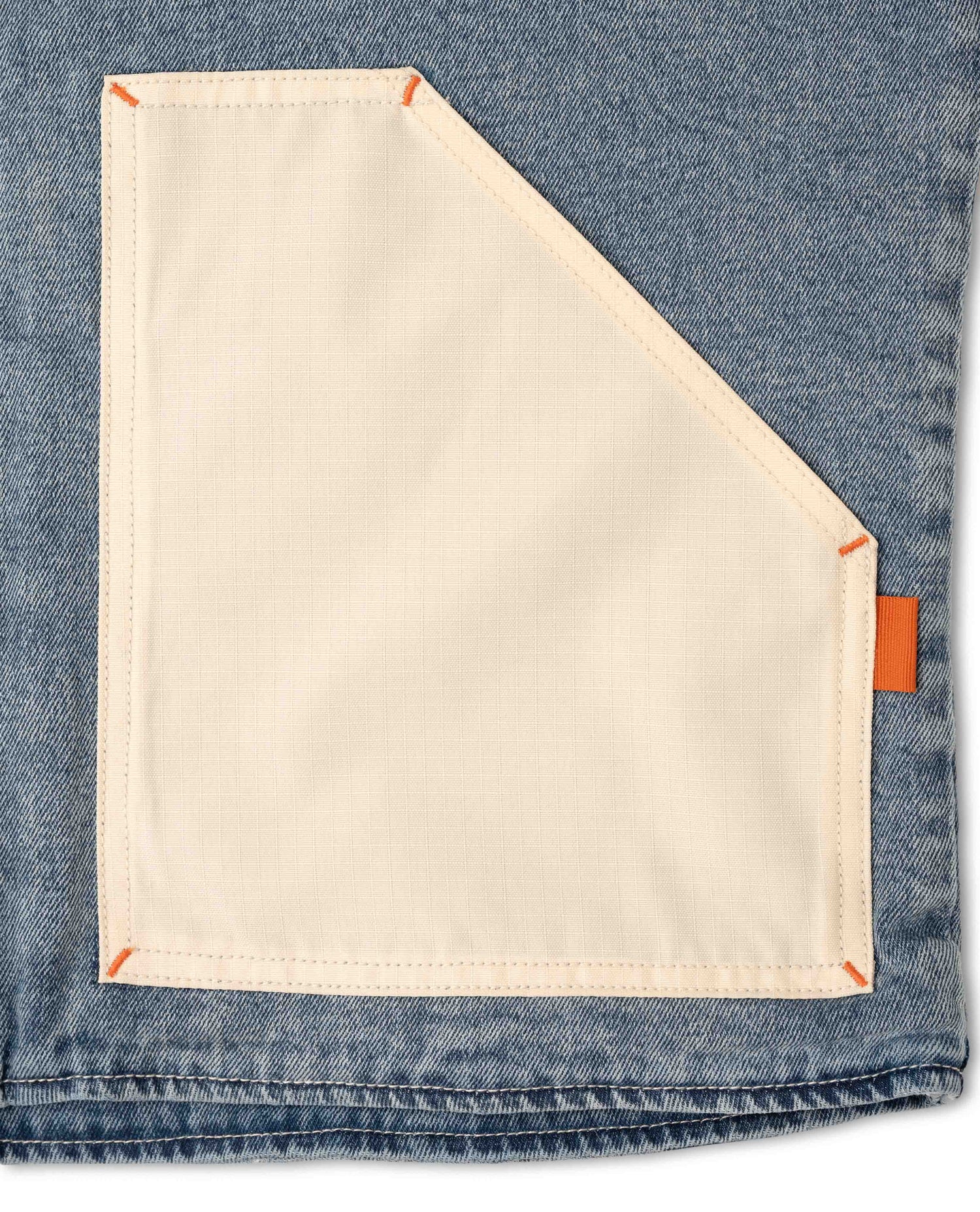 Close-up of a pocket on a denim fabric with orange stitching.