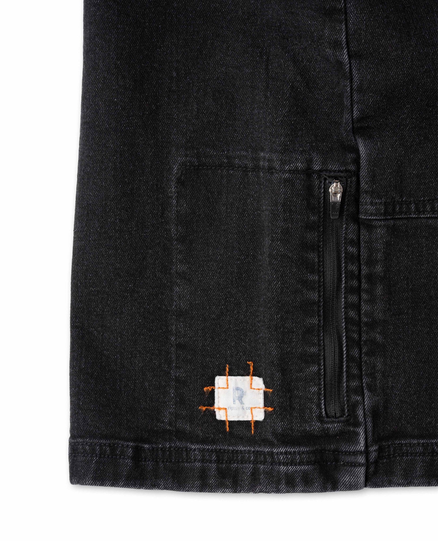 Black denim jacket with a small embroidered logo on a white background