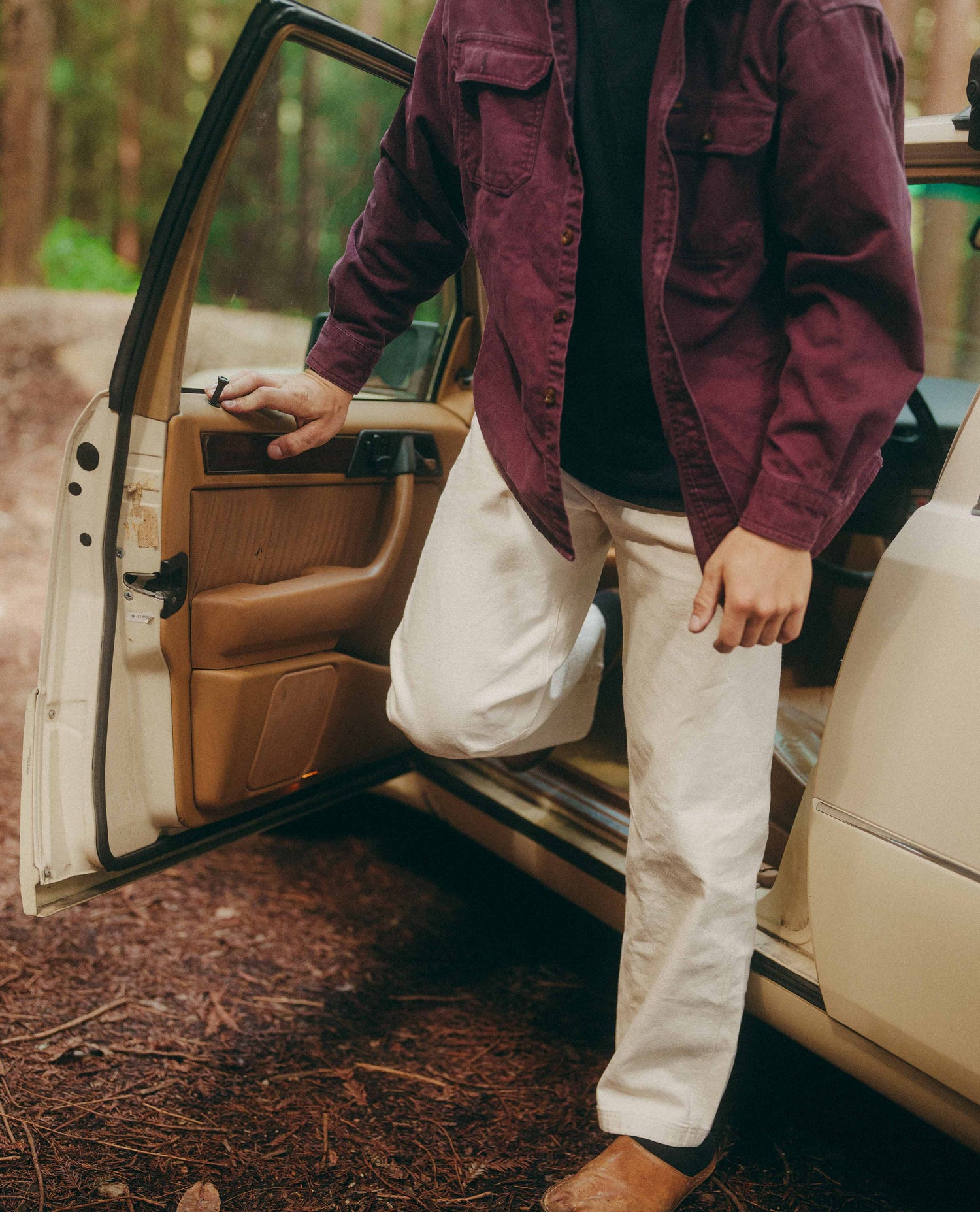 Person getting into a car in a forest setting