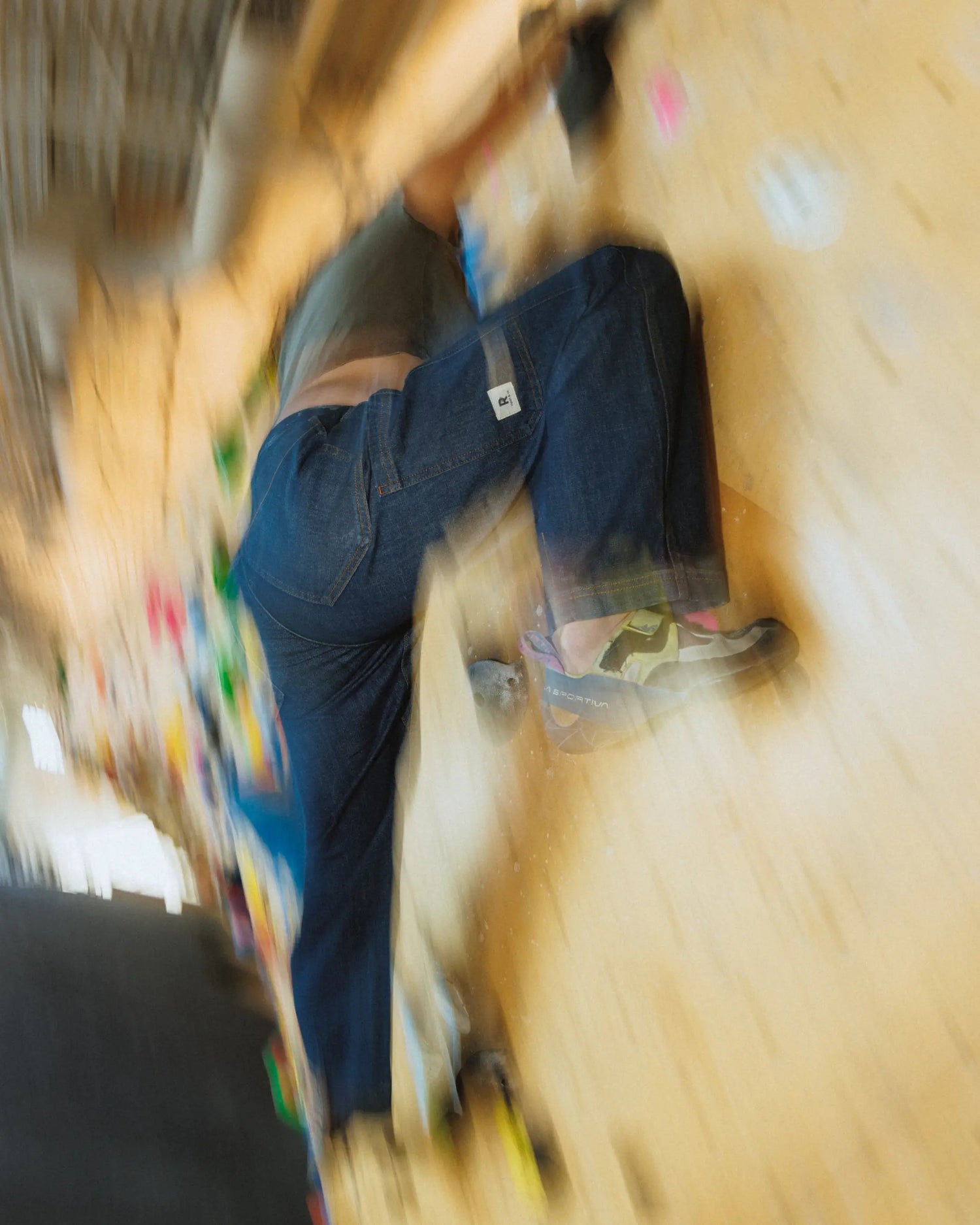Blurry image of woman leg in blue pants on a climbing gym wall 