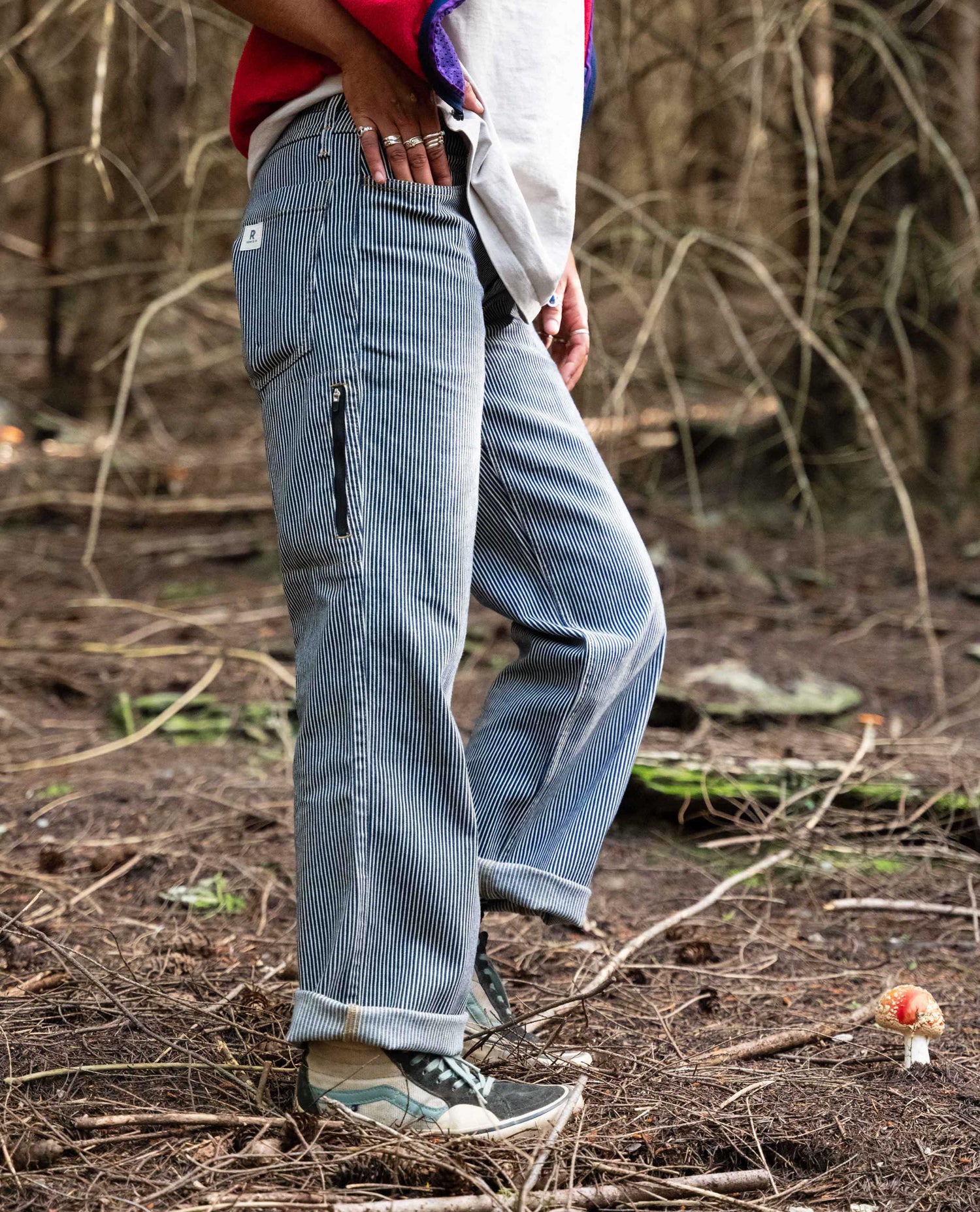 Person wearing blue corduroy pants walking through a forest