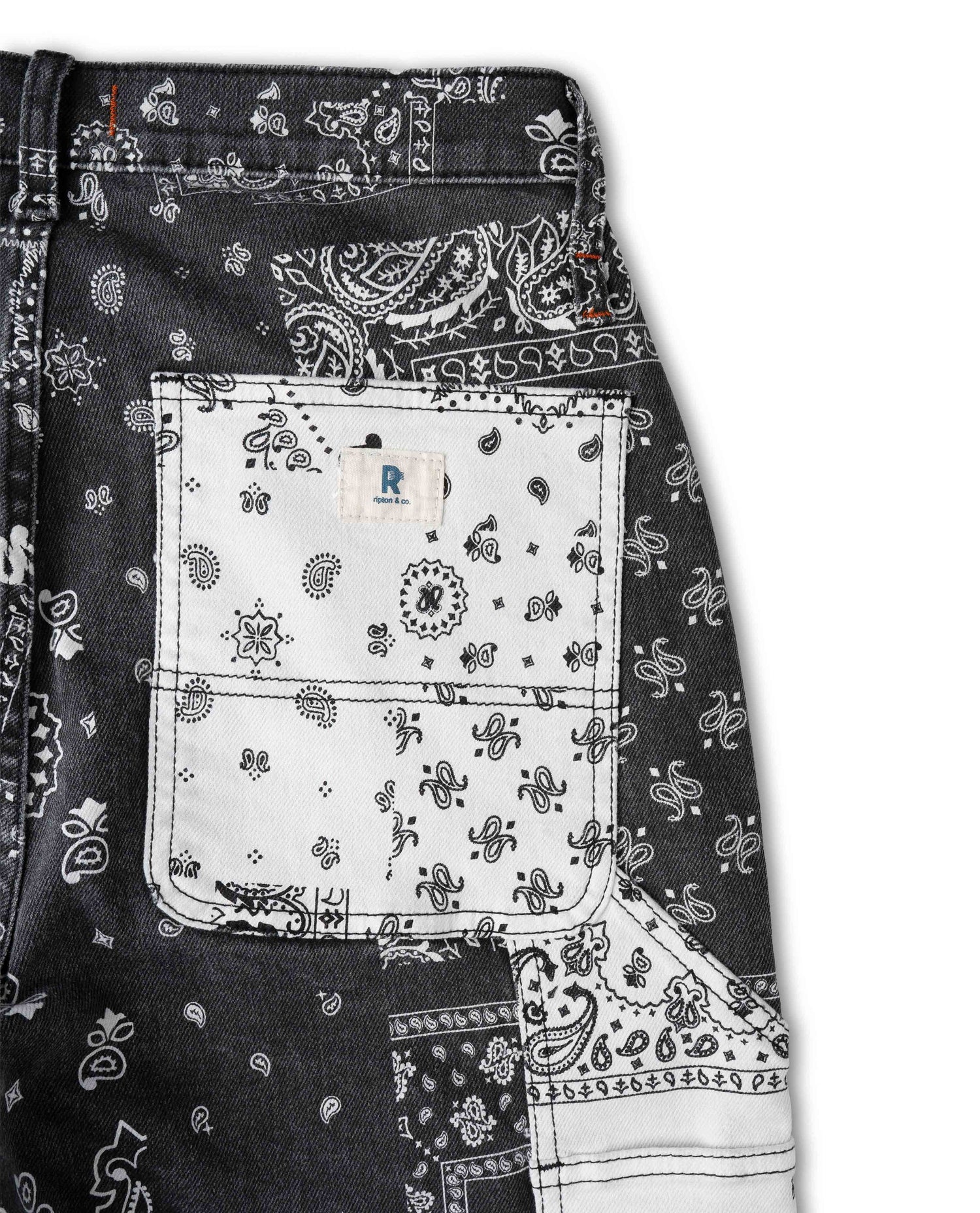 Close up photo of bandana printed pant pocket. The pocket is white, with a white and blue Ripton logo. The background of the photo is white. 