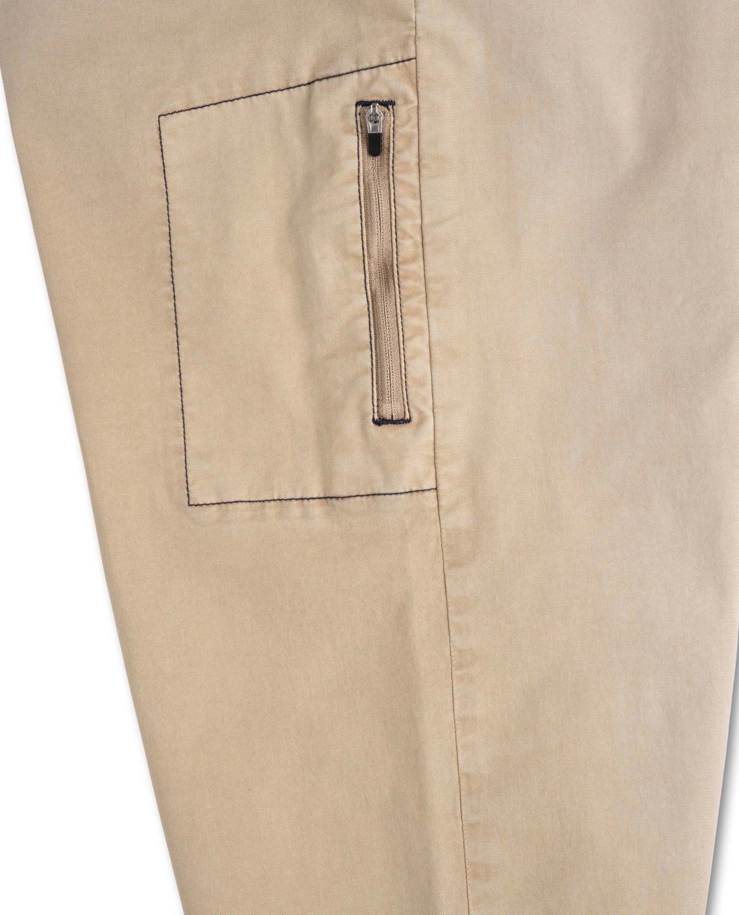 Close-up of beige pants with a pocket and zipper detail on a white background