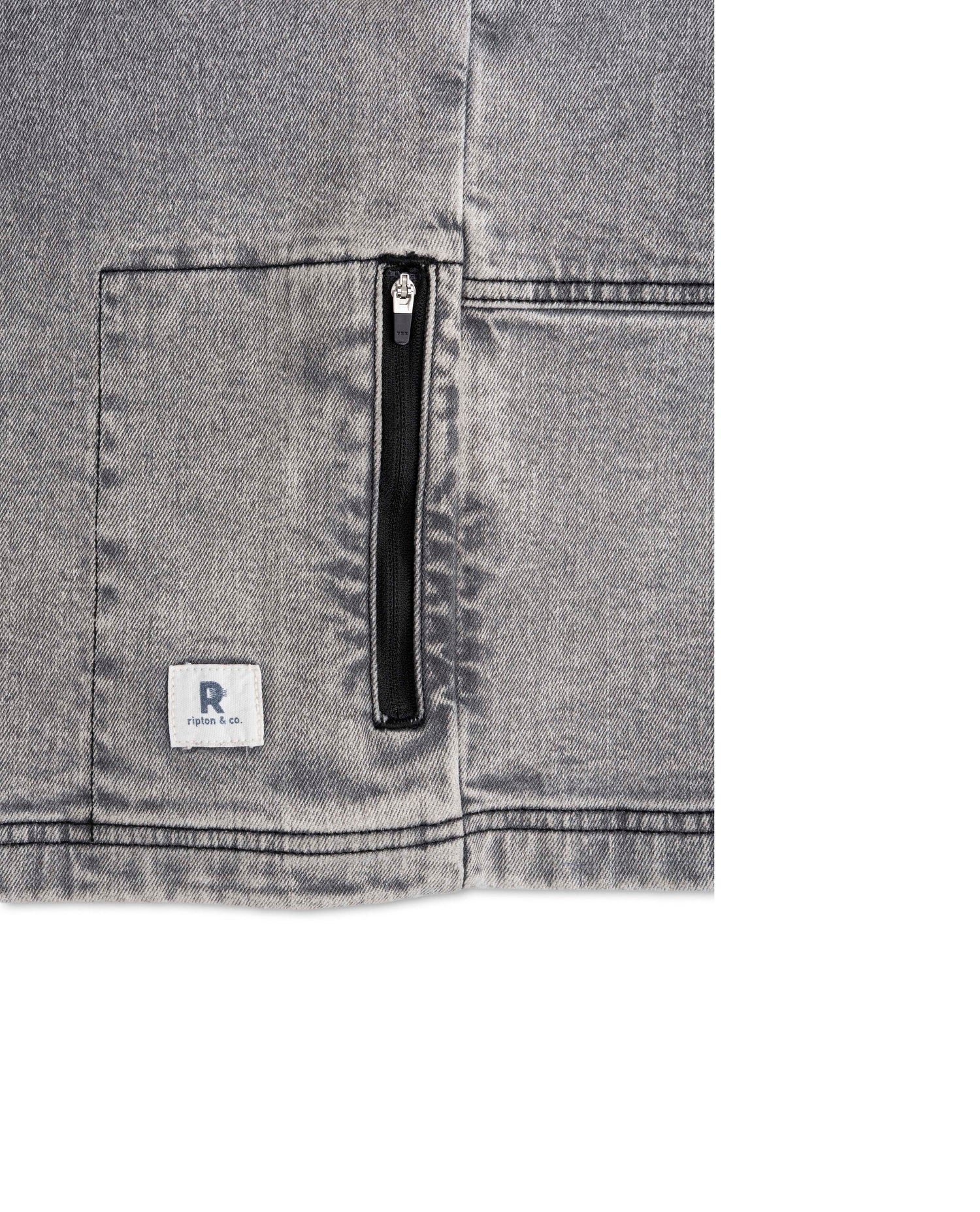 Close-up of a gray denim pocket with a zipper and brand logo on a white background
