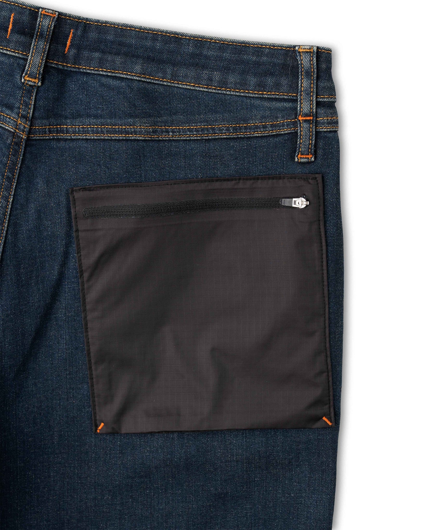 Close-up of a blue denim pocket with a black zippered pocket on a white background