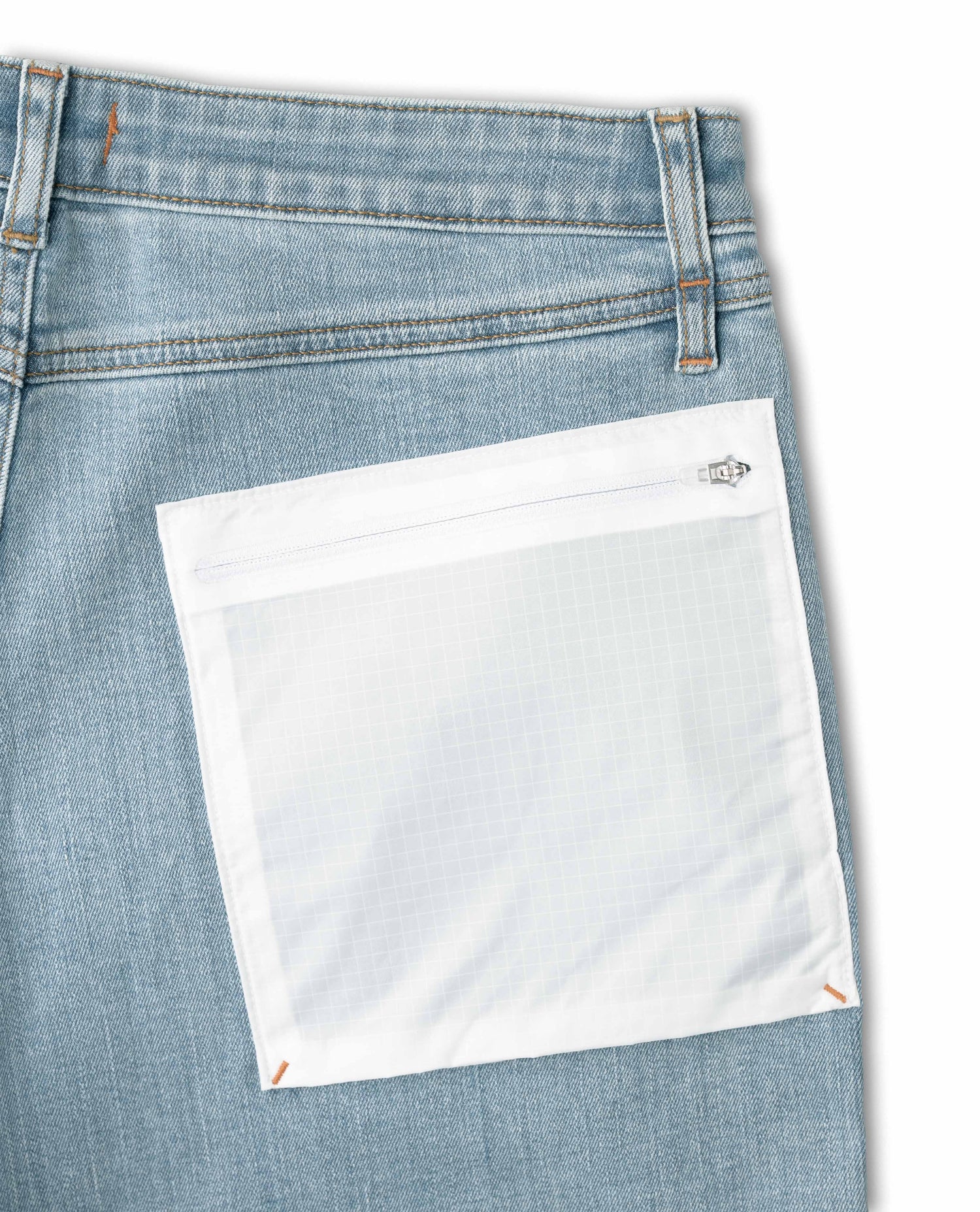 Close-up of a blue denim pocket with a white patch on a white background