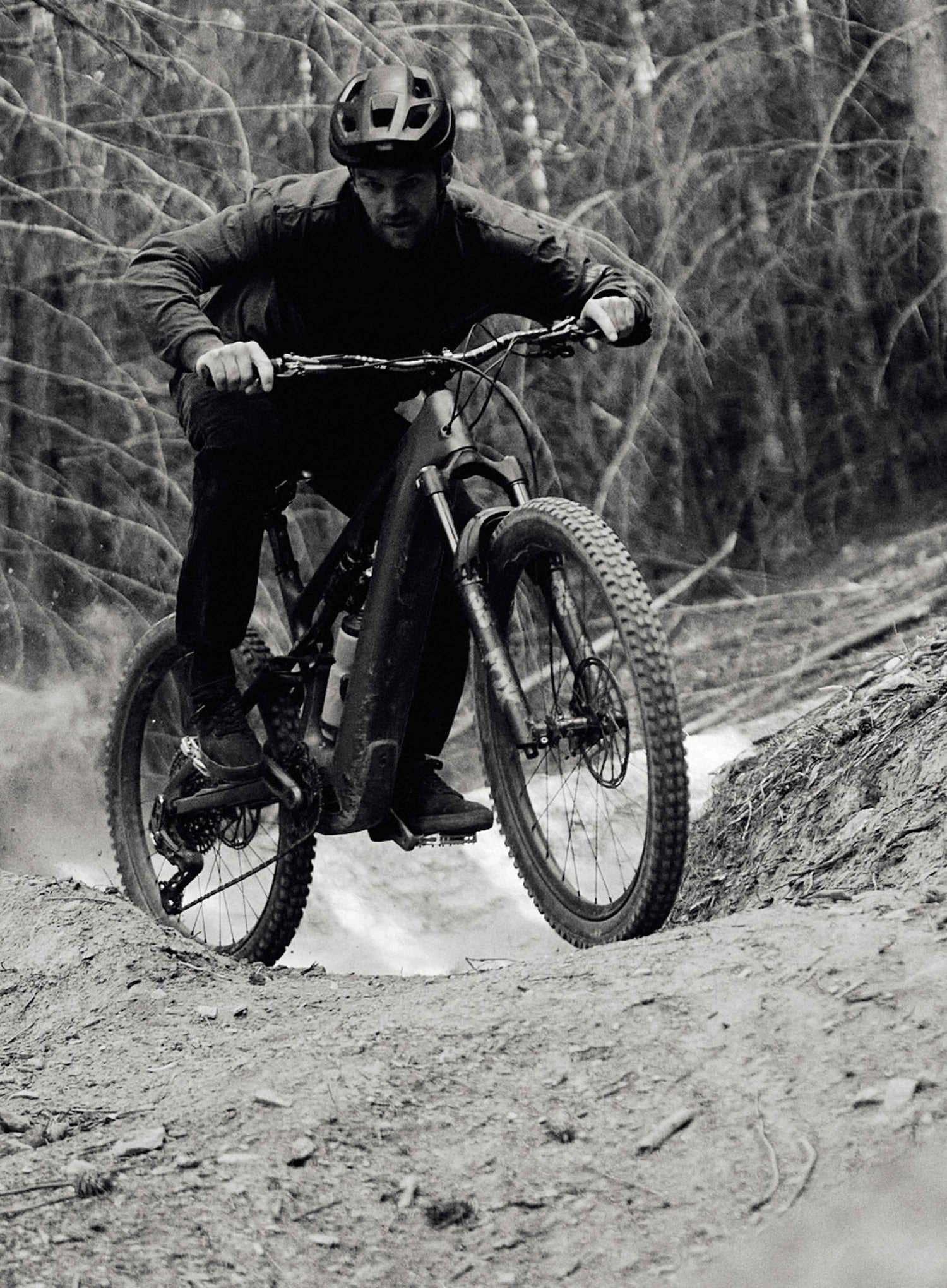Person riding a mountain bike on a trail with trees in the background