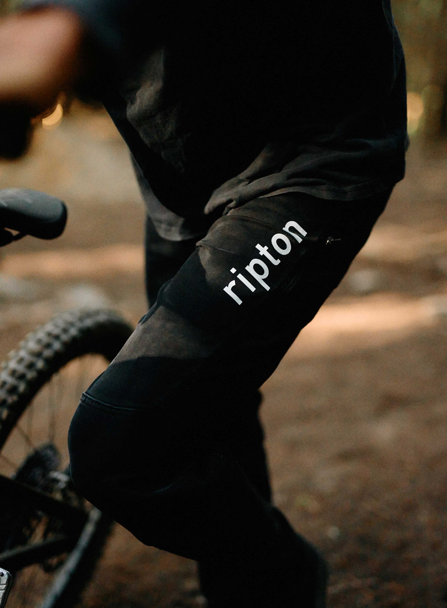 Person riding a bike with 'ripton' branding on their sleeve.