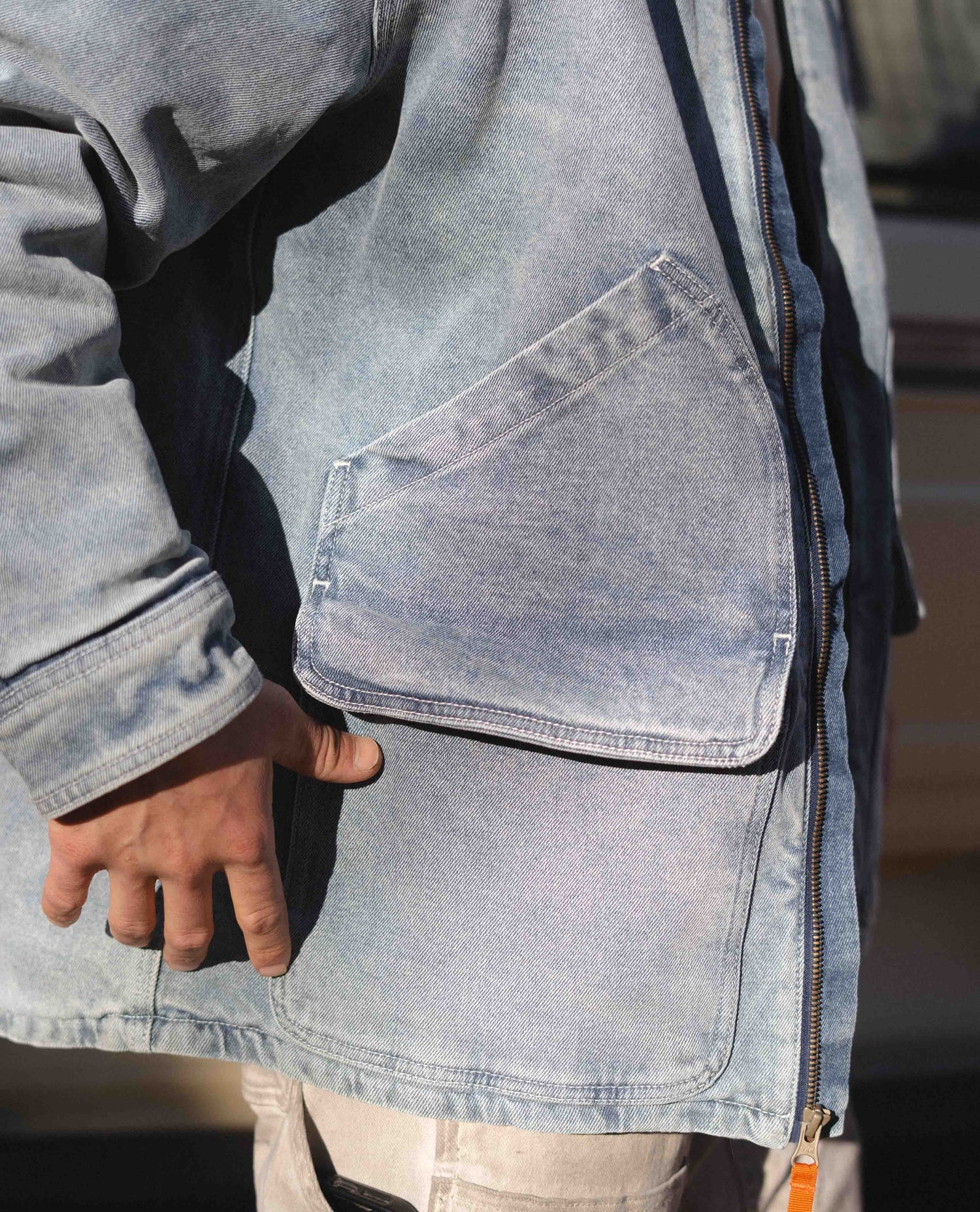 Person wearing a light blue denim jacket with a pocket detail. Color:Light