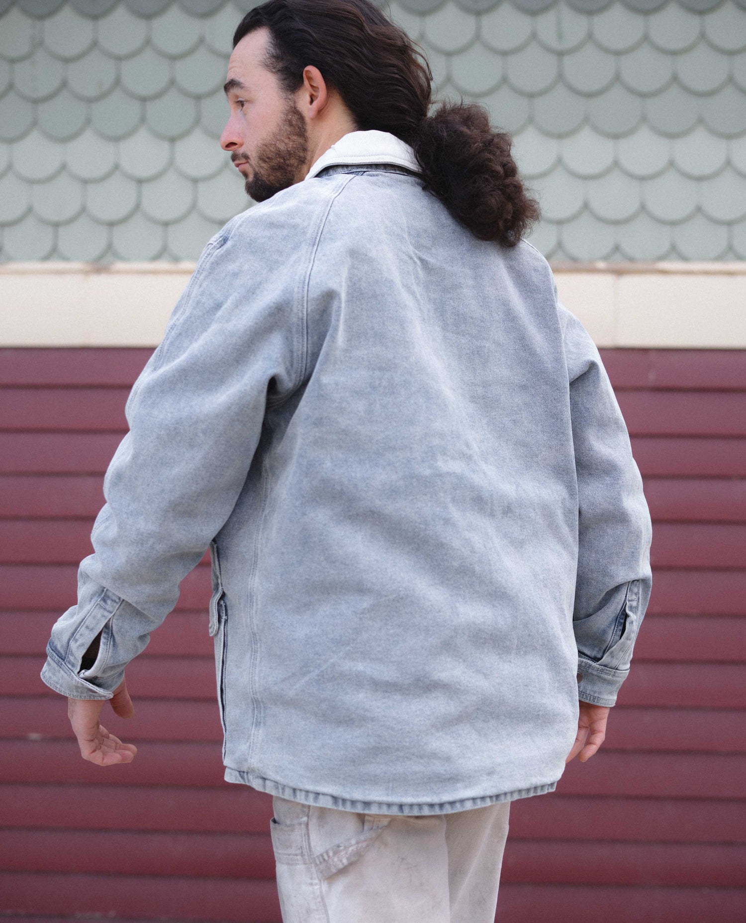 Person wearing a light gray jacket with a textured wall background Color:Light