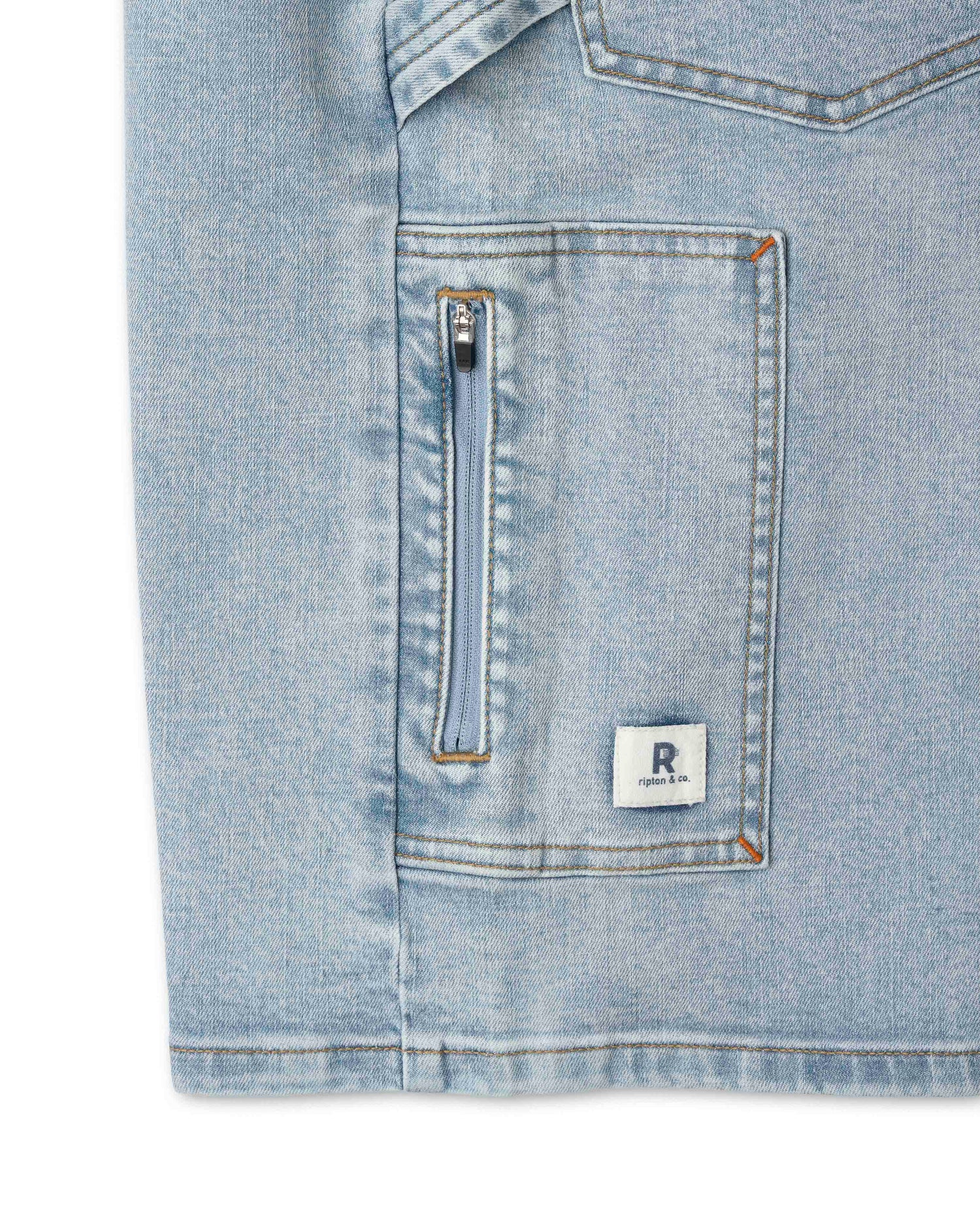 Light blue denim shirt with a zipper pocket and brand logo on a white background