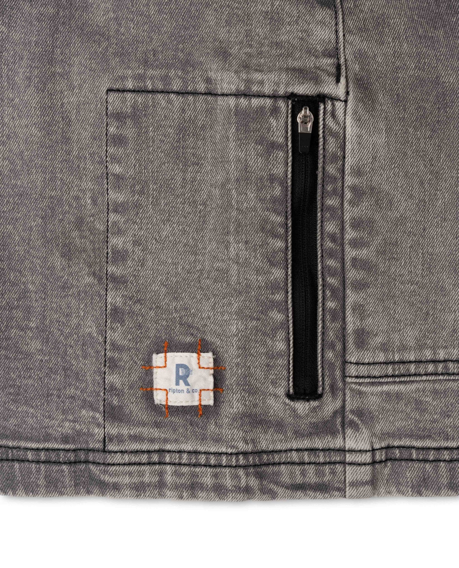 Close-up of a gray fabric pocket with a zipper and a small patch on a white background