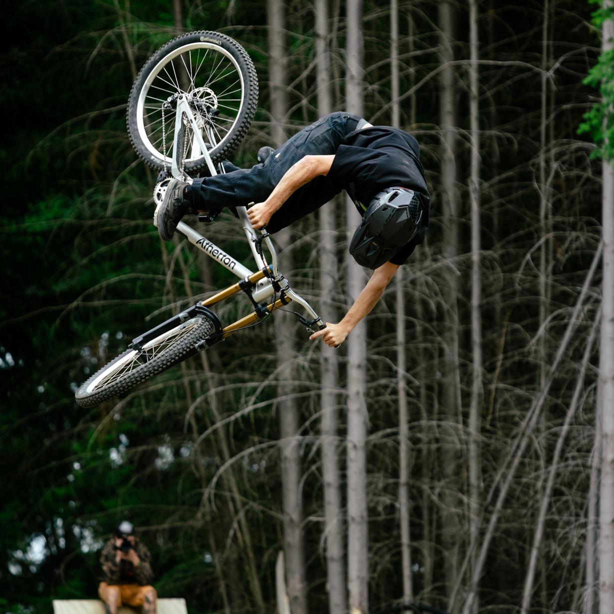 Person performing a bike trick in the air with trees in the background
