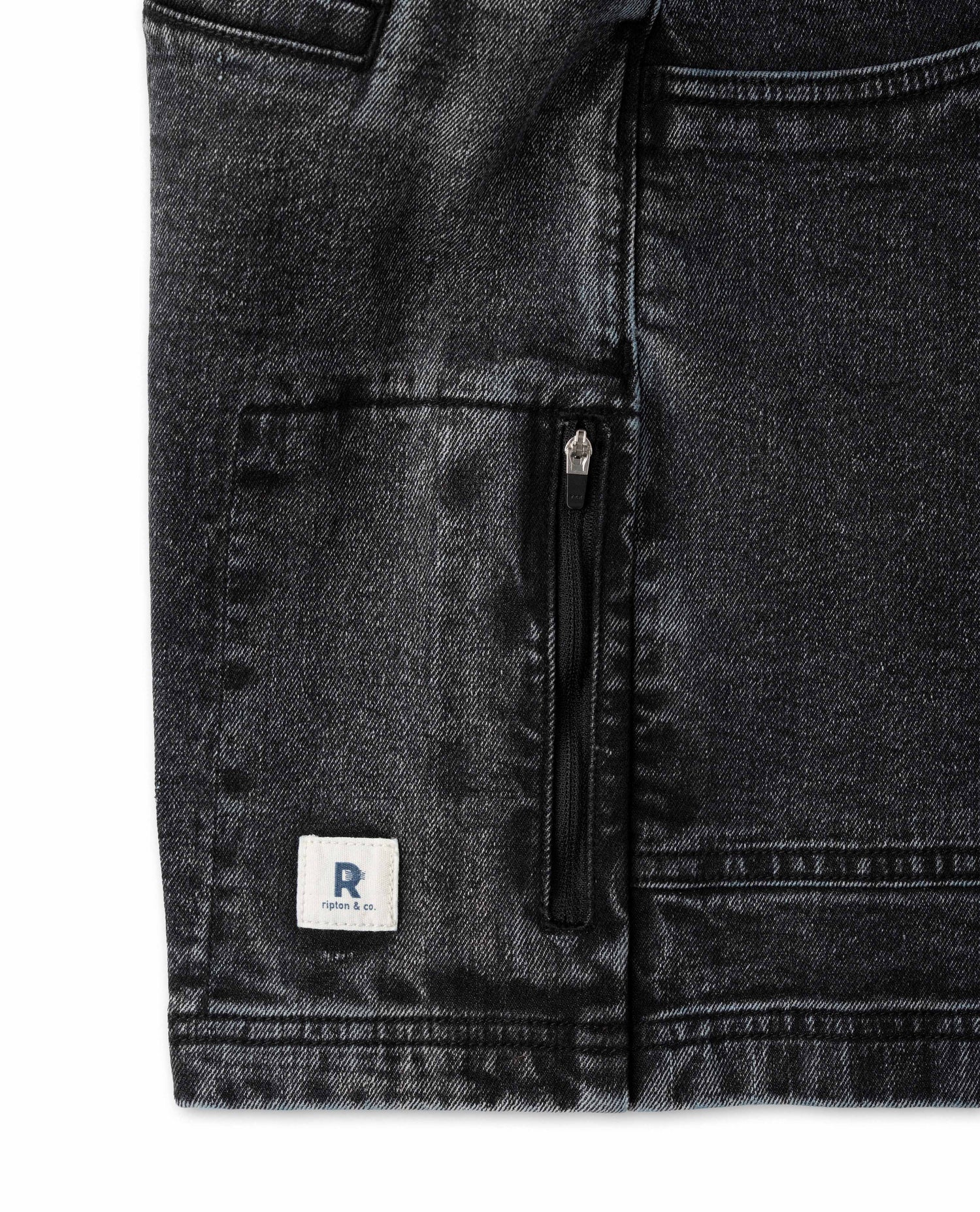 Close-up of black denim pants with a zipper pocket and a brand logo on a white background