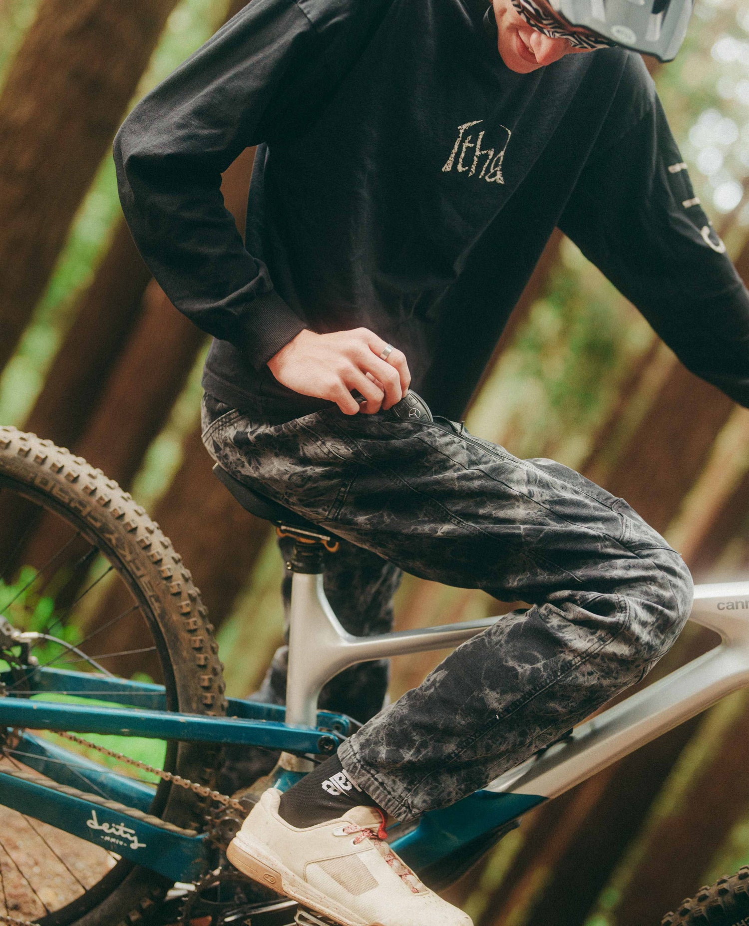 Person on a bicycle wearing a black sweatshirt with 'Italia' branding and patterned pants.