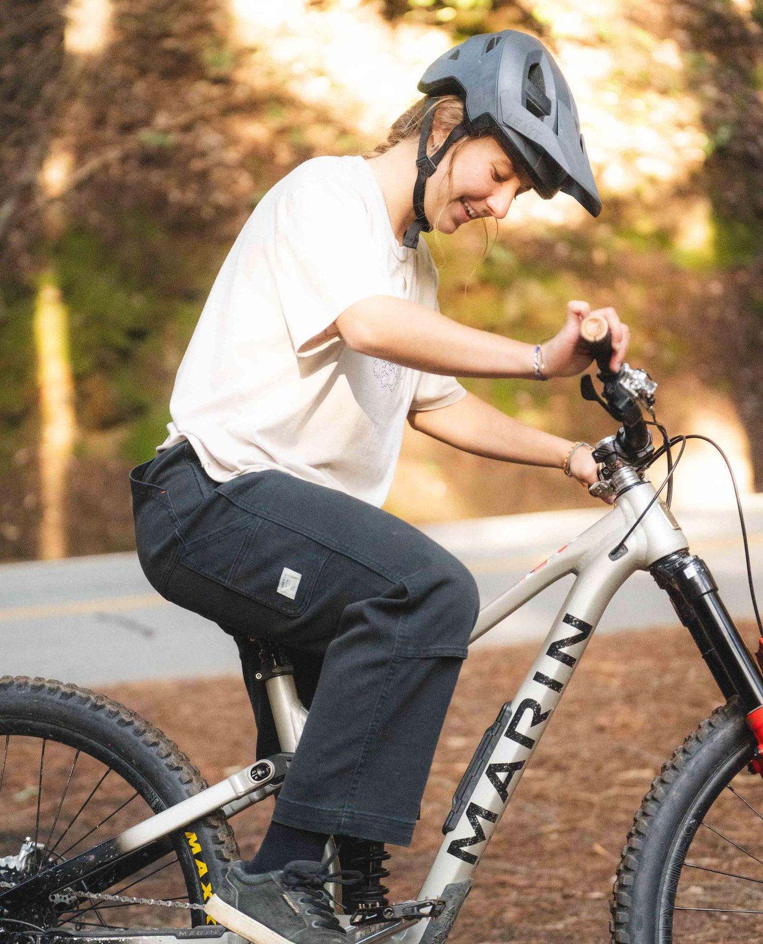 Person riding a bicycle with a helmet on a road surrounded by trees