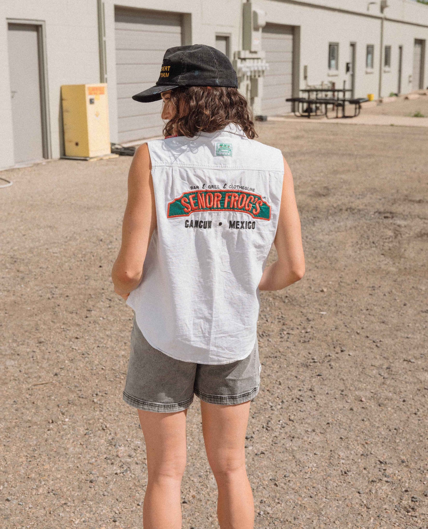 Person wearing a sleeveless shirt with 'Senor Fritz's' branding in an outdoor setting.