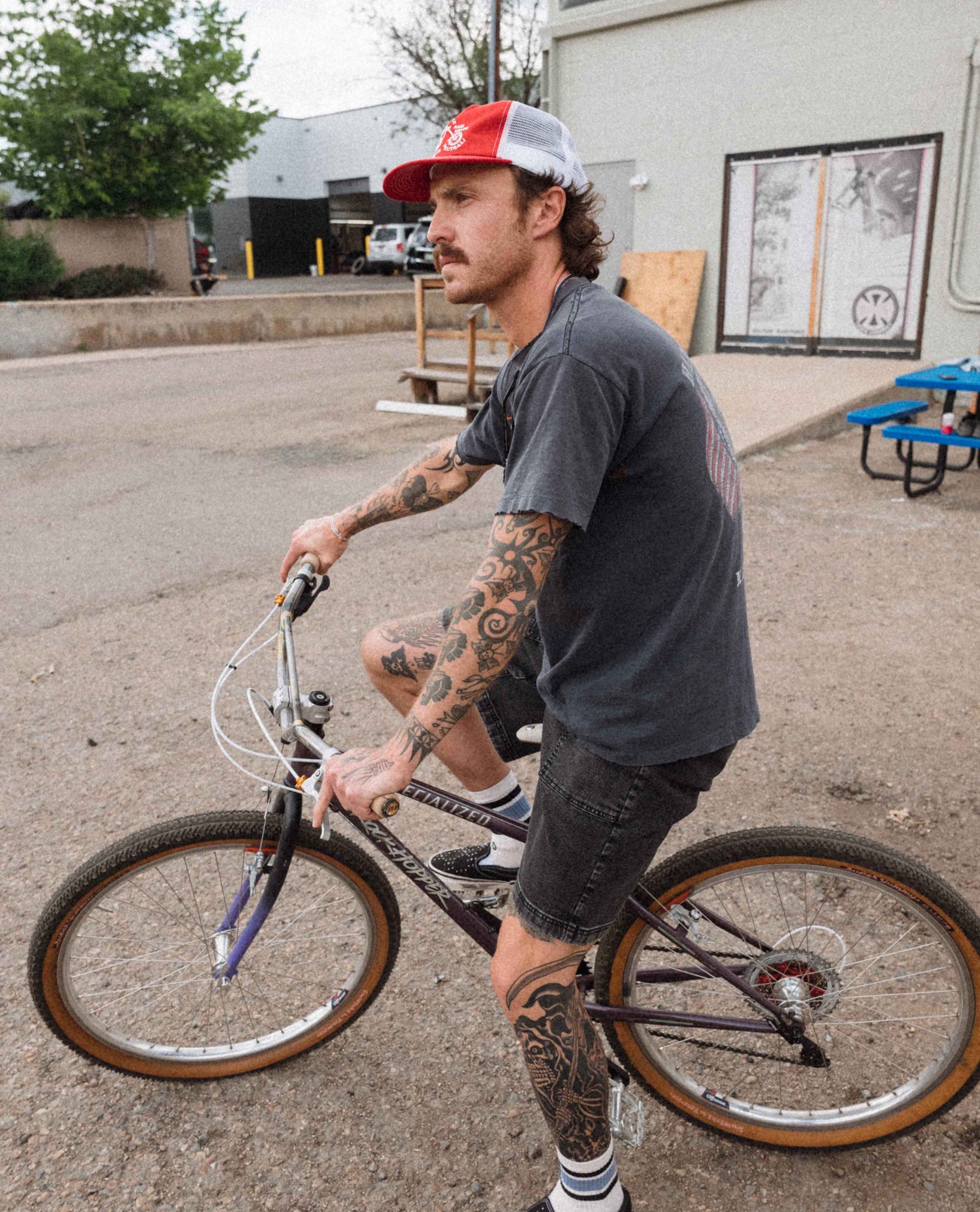 Man with tattoos riding a bicycle on a street.