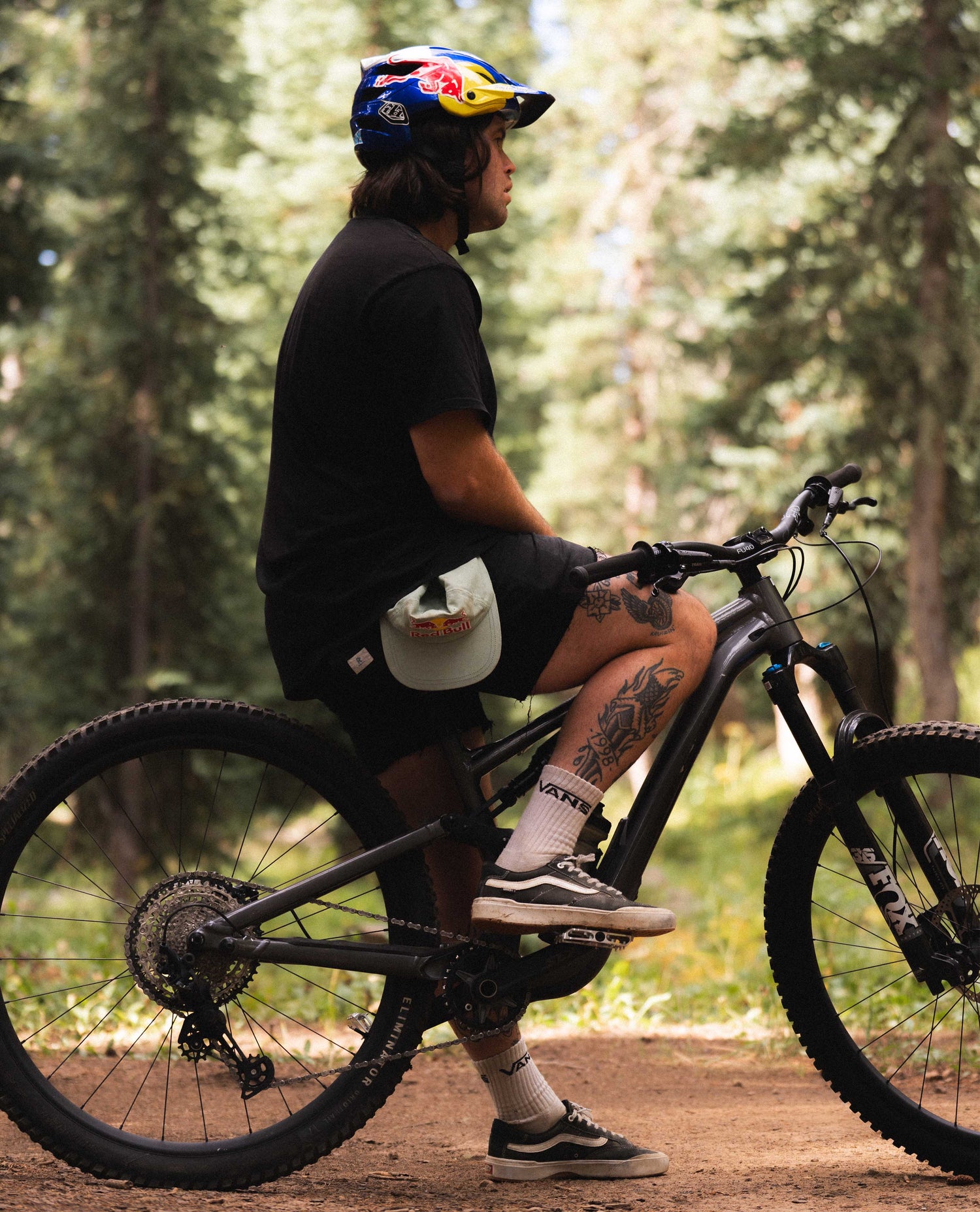 Man sitting on bike with blue helmet, black clothes, outside in the woods 