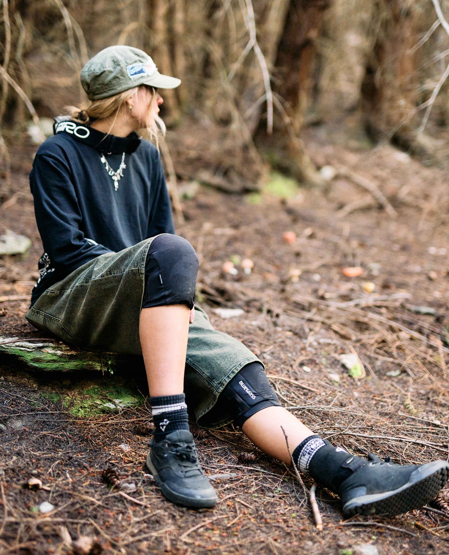 Person sitting on a log in a forest wearing outdoor gear