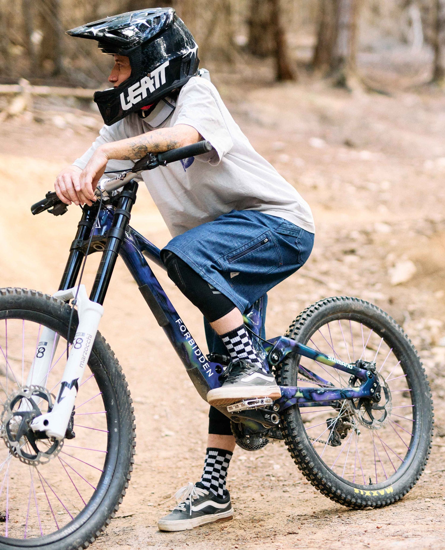 Person riding a mountain bike on a trail with a helmet and checkered socks.