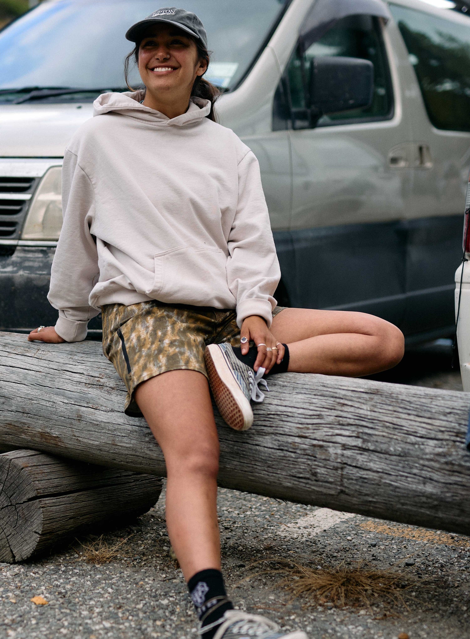 Person sitting on a log with a vehicle in the background