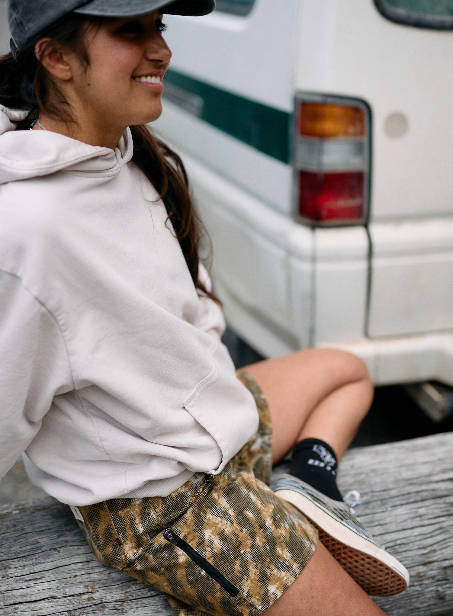 Person sitting on a log with a white van in the background